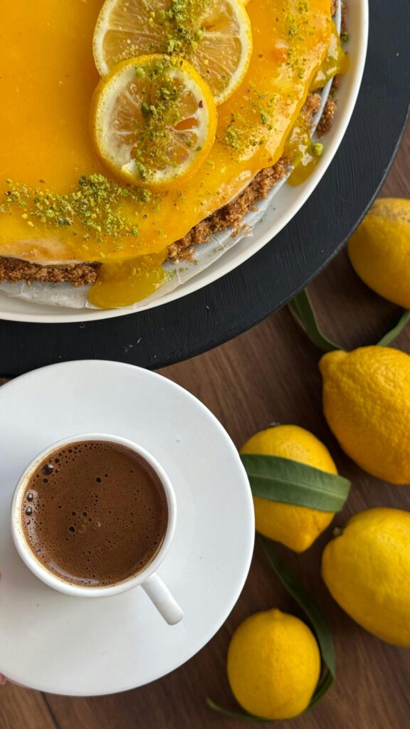 Top view of a lemon glazed cake and coffee, surrounded by fresh lemons.