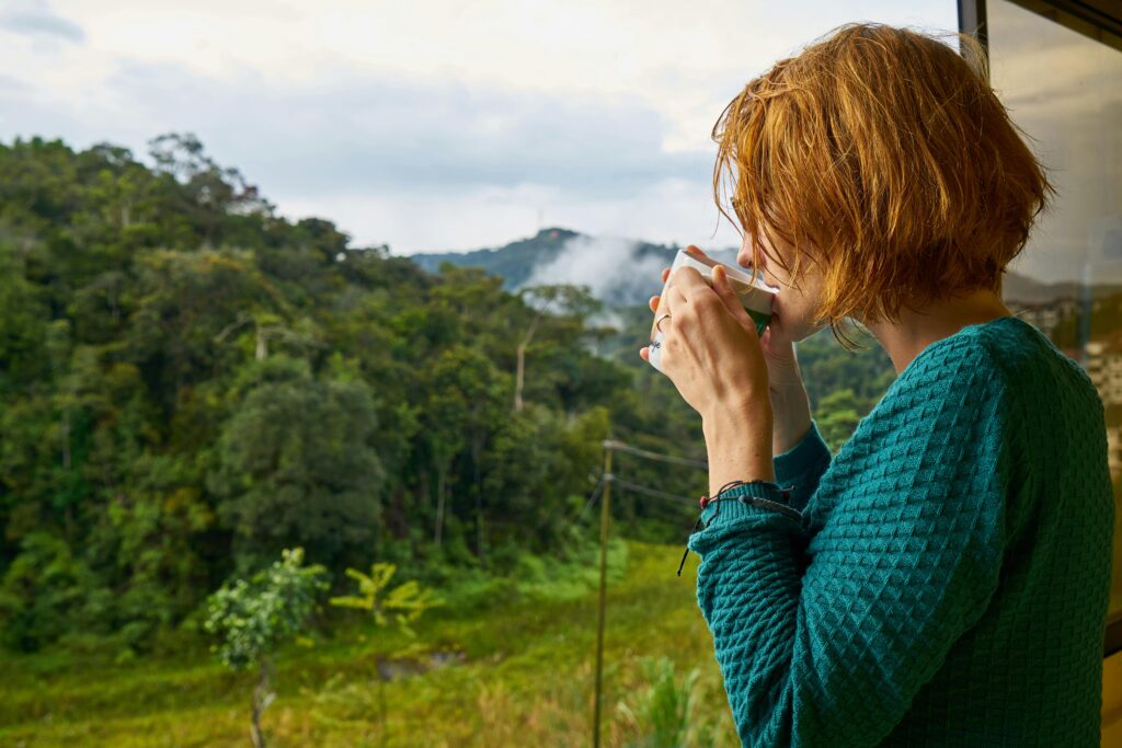 A woman enjoys morning coffee while gazing at a scenic mountain view.